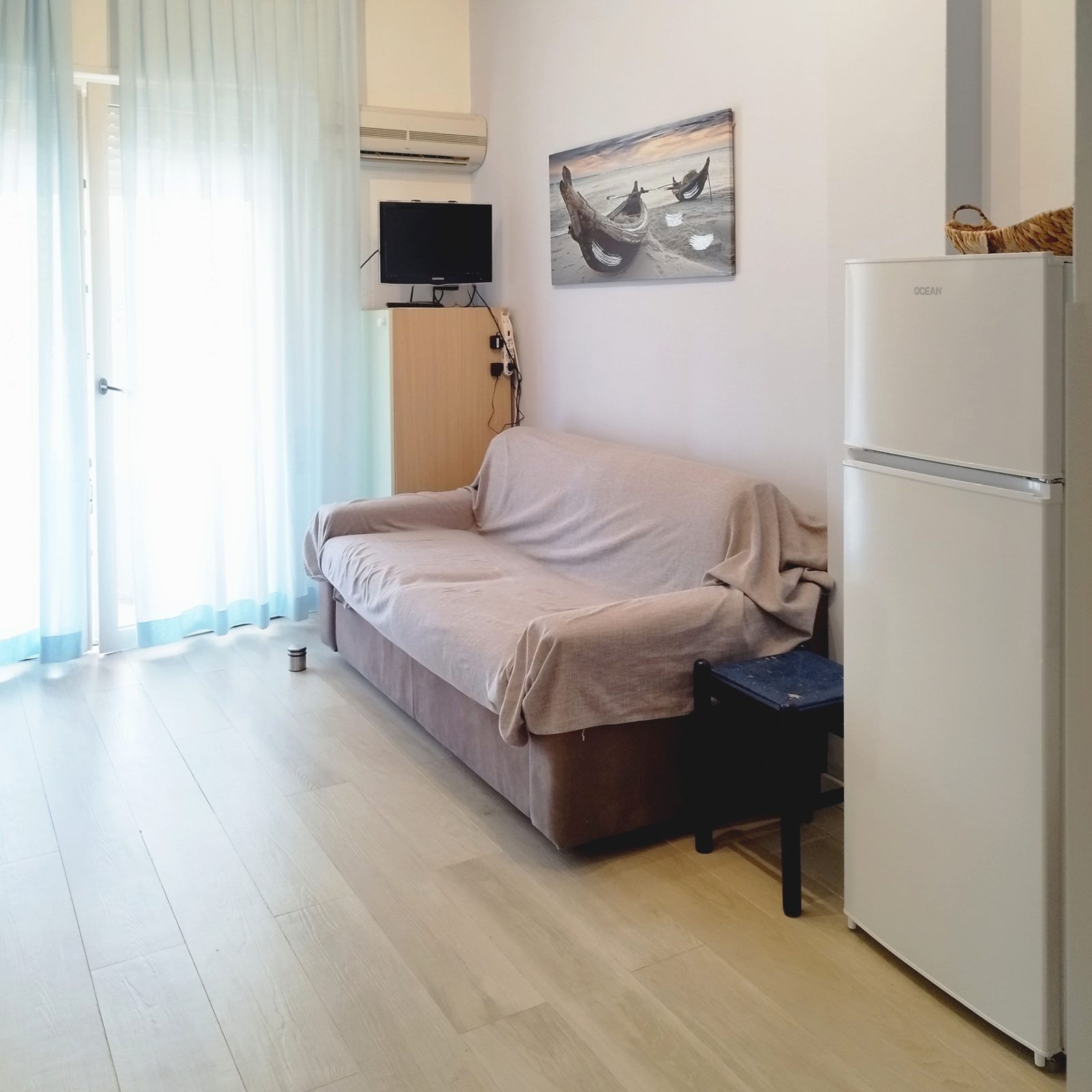 Soggiorno con divano e quadro marino dell'appartamento PhotoWalkTour House a Lido di Jesolo